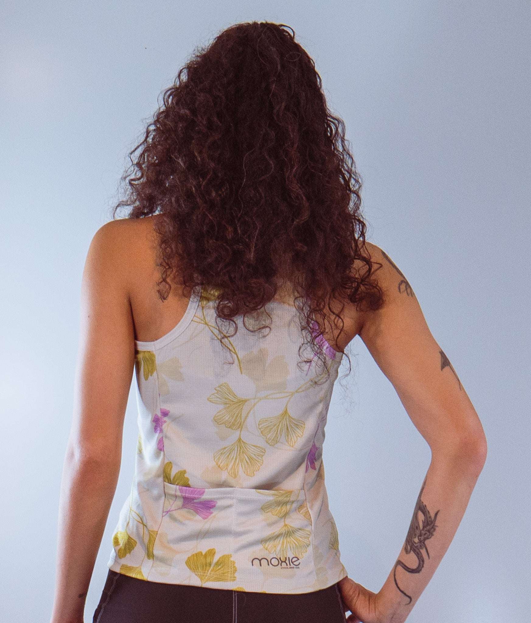 Women's sleeveless bike jersey with floral design and back pocket.